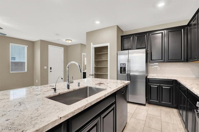 kitchen featuring dishwasher, dark cabinetry, a sink, and stainless steel fridge with ice dispenser