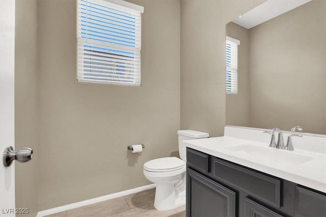 half bathroom featuring toilet, tile patterned floors, baseboards, and vanity