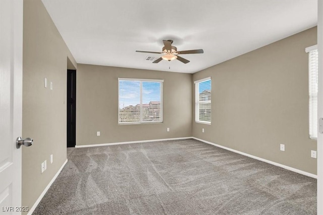 carpeted spare room with ceiling fan, visible vents, and baseboards