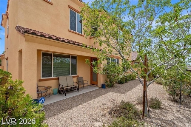 rear view of property with a tile roof and stucco siding