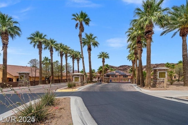 view of street with a gate, curbs, and a gated entry