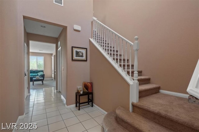 stairway featuring carpet flooring, visible vents, baseboards, and tile patterned floors