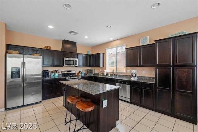 kitchen with visible vents, a kitchen island, dark stone countertops, stainless steel appliances, and a sink