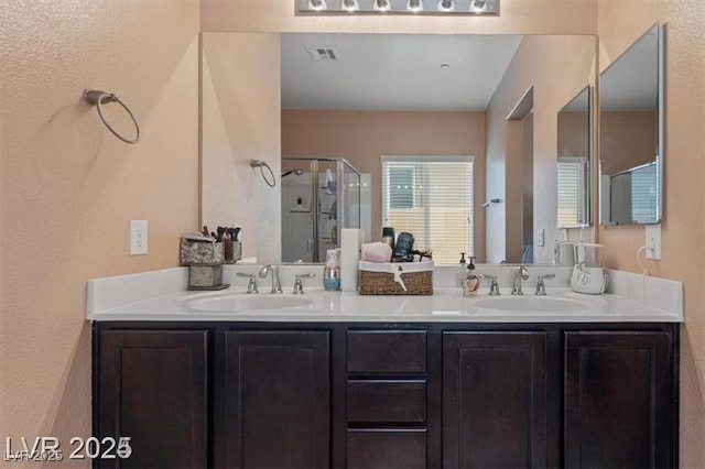 bathroom featuring a stall shower, visible vents, a sink, and double vanity