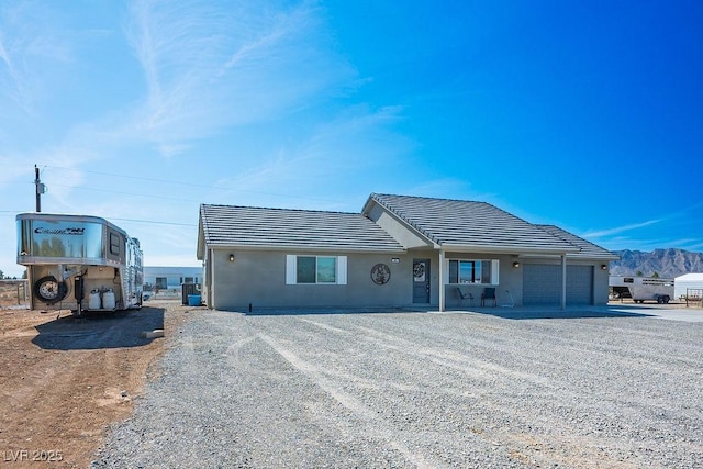 ranch-style house with a garage, driveway, and stucco siding