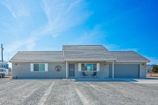 single story home with concrete driveway, a tiled roof, an attached garage, and stucco siding