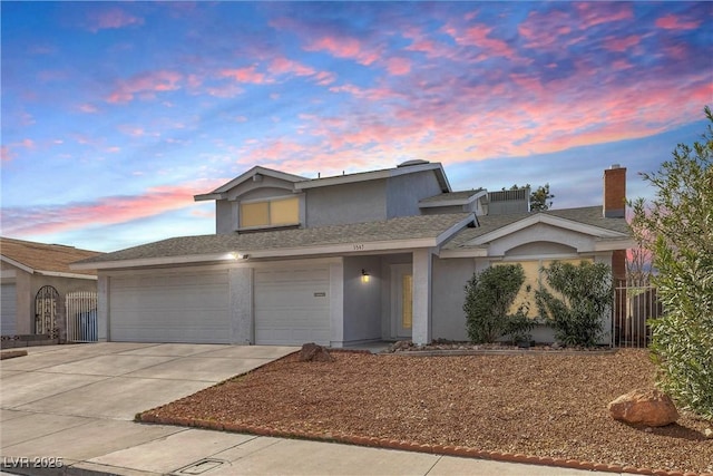 traditional home featuring a garage, driveway, fence, and stucco siding