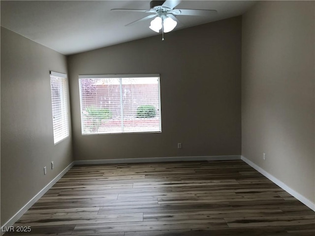 empty room featuring lofted ceiling, wood finished floors, a ceiling fan, and baseboards