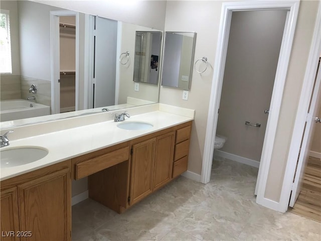 bathroom with a bathtub, a walk in closet, a sink, and double vanity