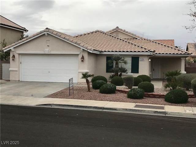 mediterranean / spanish-style house with a garage, driveway, a tiled roof, and stucco siding