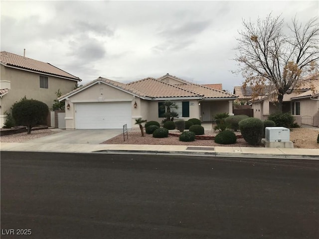 view of front of home featuring a garage, a tile roof, concrete driveway, and stucco siding