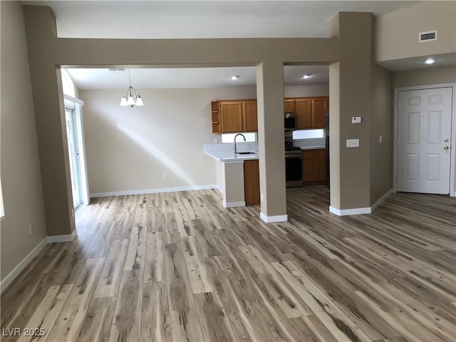 unfurnished living room with a notable chandelier, light wood-style flooring, and baseboards