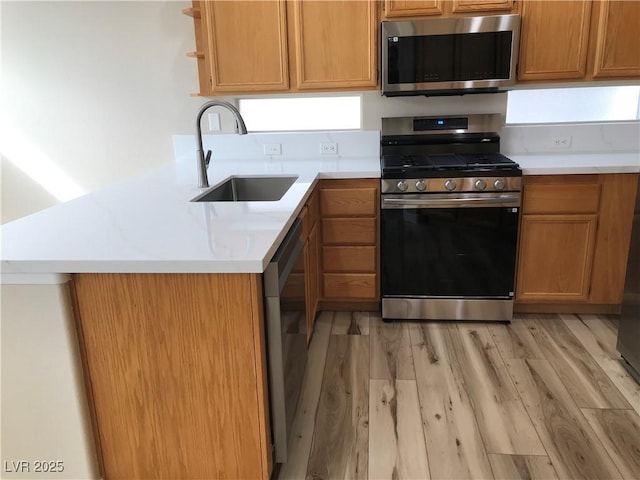 kitchen featuring open shelves, stainless steel appliances, light countertops, a sink, and light wood-type flooring