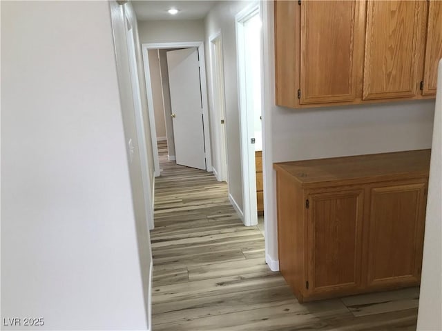 hallway featuring light wood-type flooring and baseboards