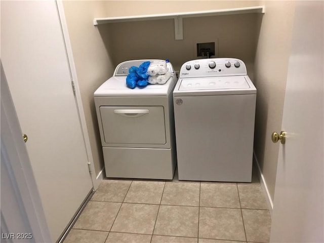 laundry room featuring laundry area, washing machine and dryer, baseboards, and light tile patterned flooring