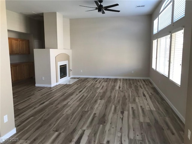 331 Mount Hope St, Henderson, NV 89014 - unfurnished living room featuring wood finished floors, a ceiling fan, plenty of natural light, and a fireplace with flush hearth