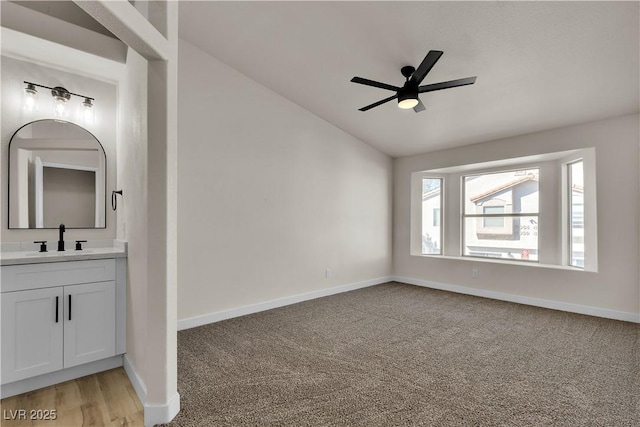 empty room with lofted ceiling, a sink, baseboards, and ceiling fan