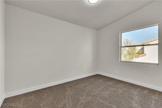 unfurnished room featuring lofted ceiling, dark colored carpet, and baseboards