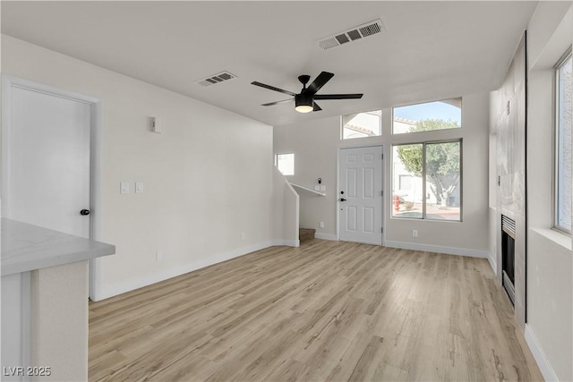 unfurnished living room with a ceiling fan, visible vents, and light wood-style floors