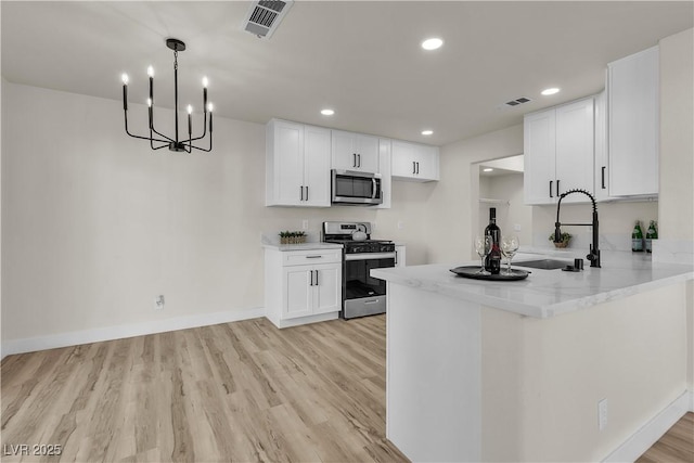 kitchen with visible vents, white cabinets, light wood-style flooring, stainless steel appliances, and a sink