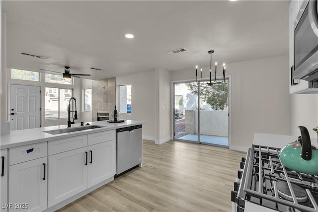 kitchen with light wood finished floors, visible vents, appliances with stainless steel finishes, white cabinets, and a sink