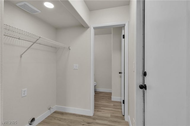 laundry area featuring laundry area, light wood-style flooring, visible vents, and baseboards