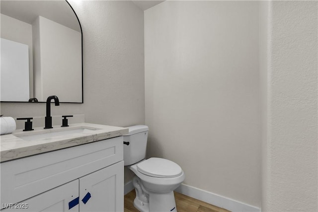 bathroom featuring toilet, wood finished floors, vanity, and baseboards