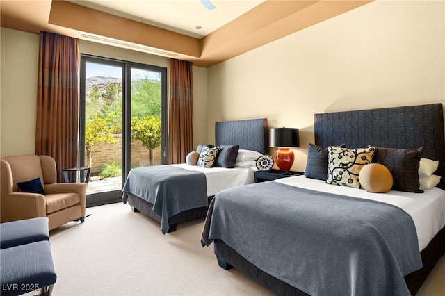 bedroom with access to exterior, a tray ceiling, and light colored carpet