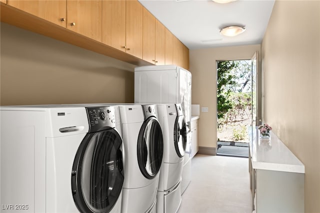 laundry area with light tile patterned floors, washing machine and clothes dryer, and cabinet space