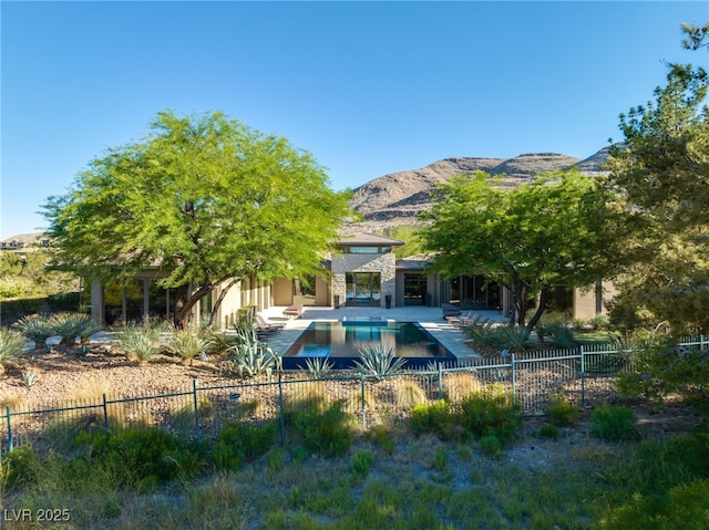 rear view of property featuring fence private yard, a mountain view, a fenced in pool, stucco siding, and a patio area