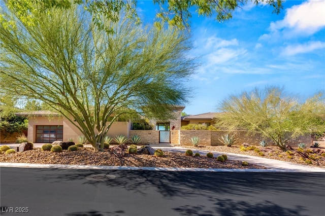 view of front of property with a fenced front yard, a gate, a garage, and stucco siding