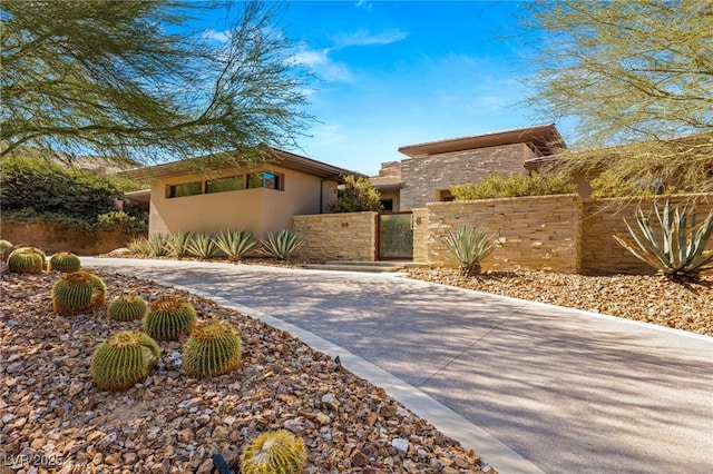 view of front of home with driveway, a fenced front yard, a gate, and stucco siding