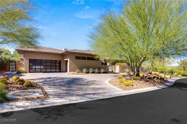 view of front of house with a garage, driveway, and stucco siding