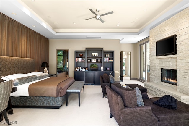 bedroom with carpet floors, a raised ceiling, multiple windows, and a fireplace