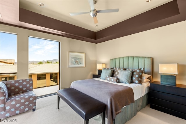 bedroom featuring a tray ceiling, carpet, a ceiling fan, and access to exterior