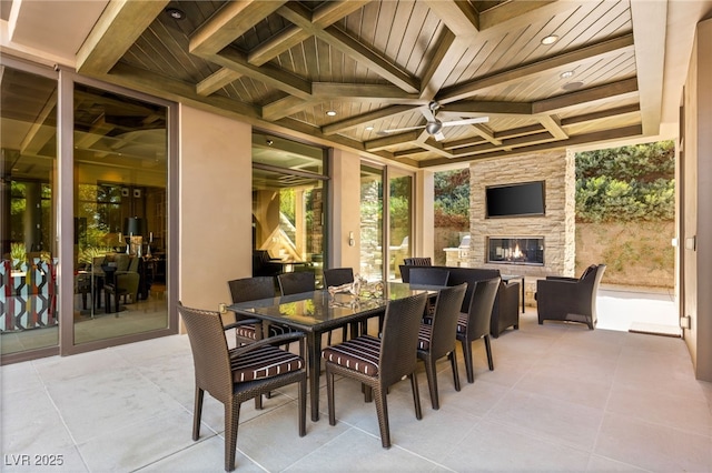 view of patio / terrace with an outdoor stone fireplace, outdoor dining area, and a ceiling fan