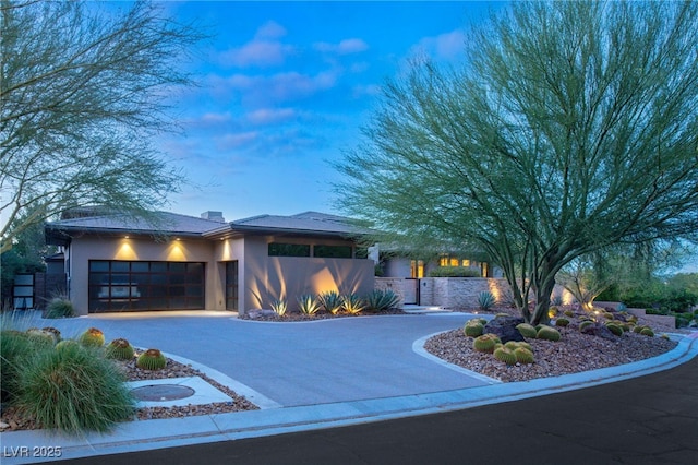 view of front of property featuring a chimney, stucco siding, concrete driveway, fence, and a garage