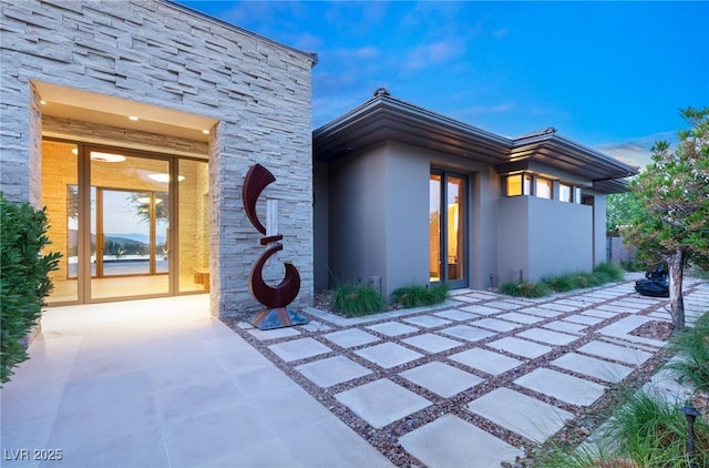 entrance to property featuring stone siding and stucco siding