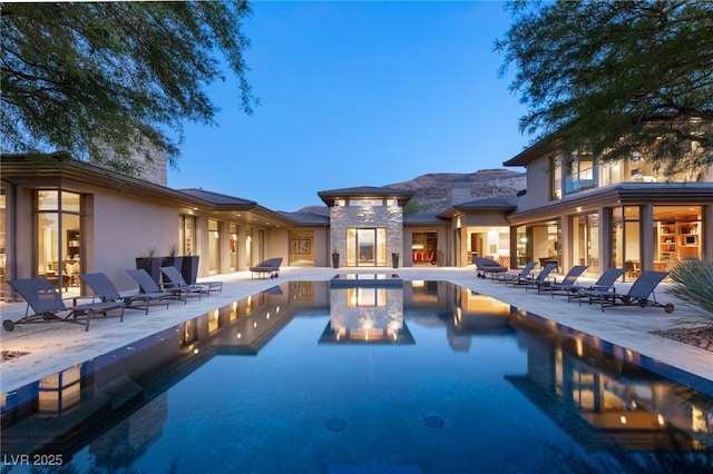 pool at dusk featuring an outdoor pool and a patio