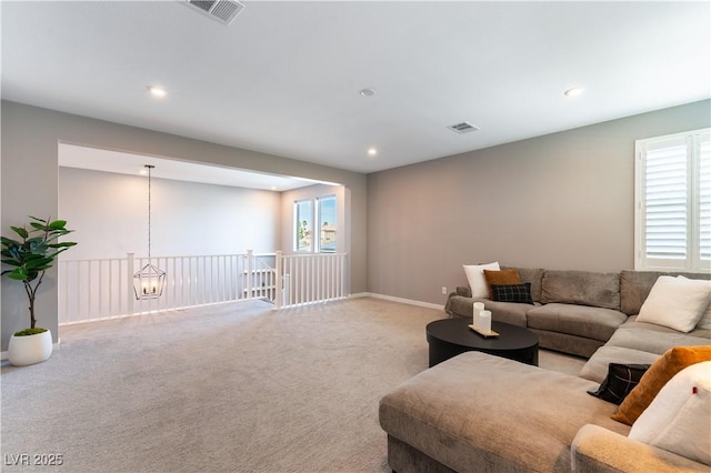 living room featuring plenty of natural light, visible vents, and carpet flooring