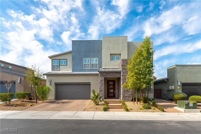 contemporary house featuring decorative driveway, stucco siding, an attached garage, a standing seam roof, and metal roof