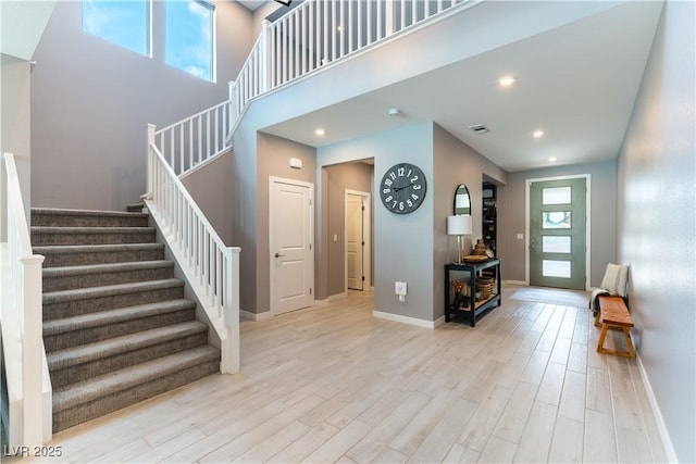 foyer entrance featuring stairway, light wood-type flooring, visible vents, and baseboards