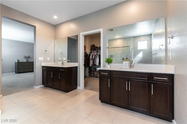 bathroom featuring a stall shower, tile patterned floors, a sink, a spacious closet, and two vanities