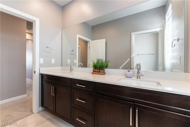 full bath with double vanity, tile patterned flooring, a sink, and baseboards