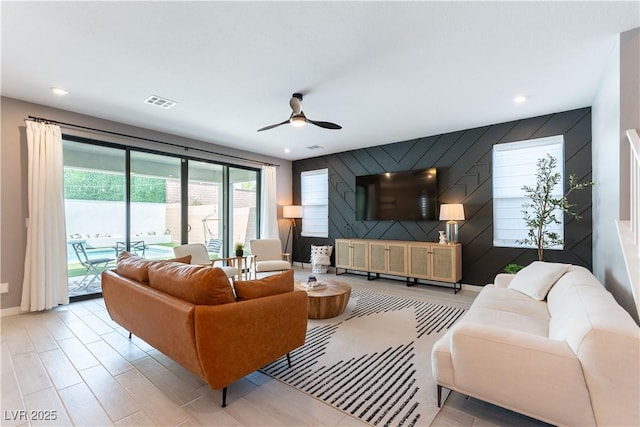 living area with baseboards, visible vents, a ceiling fan, an accent wall, and recessed lighting