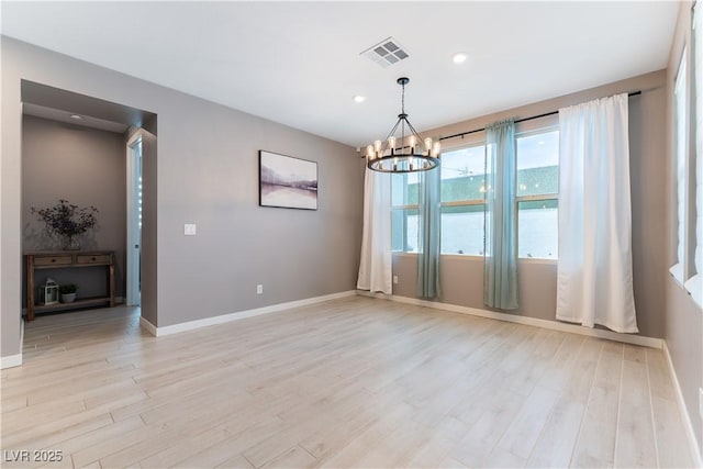 empty room with light wood-style flooring, visible vents, a chandelier, and baseboards