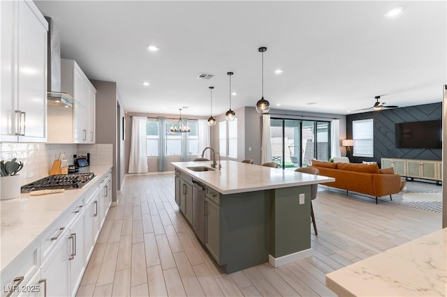 kitchen featuring a sink, visible vents, gas stovetop, white cabinets, and backsplash