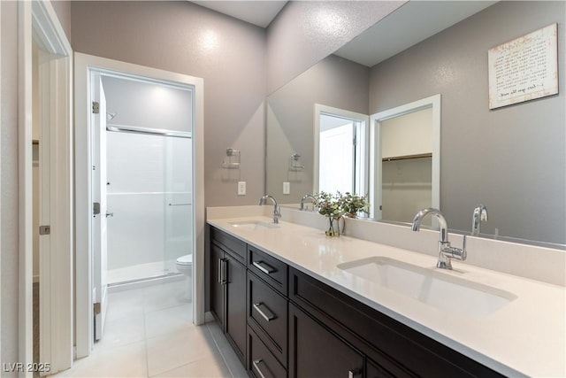 full bathroom featuring double vanity, a sink, toilet, and a shower stall