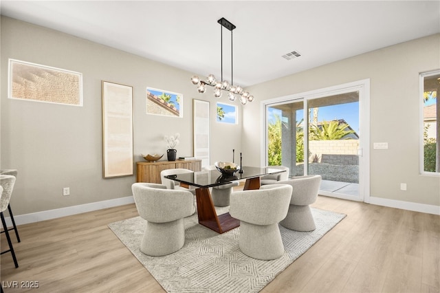 dining area with a chandelier, baseboards, visible vents, and light wood-style floors