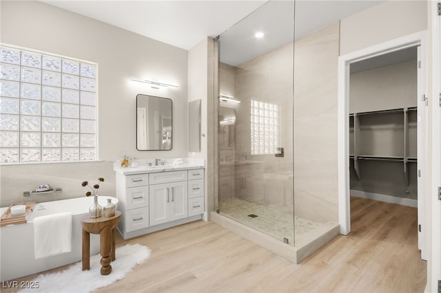 bathroom featuring a stall shower, a soaking tub, wood finished floors, and vanity